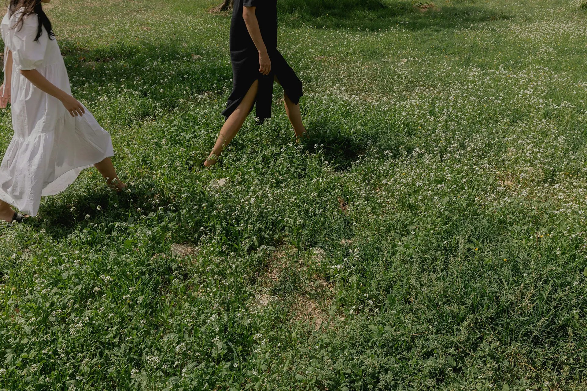 Two people walking barefoots in a meadow
