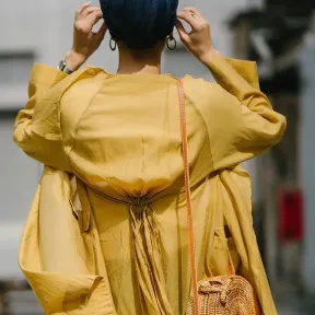 Backside of a woman wearing a yellow trench coat